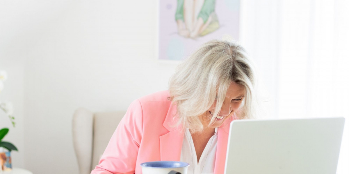Daniela Brandl Coach, die vor dem Laptop steht und lacht.