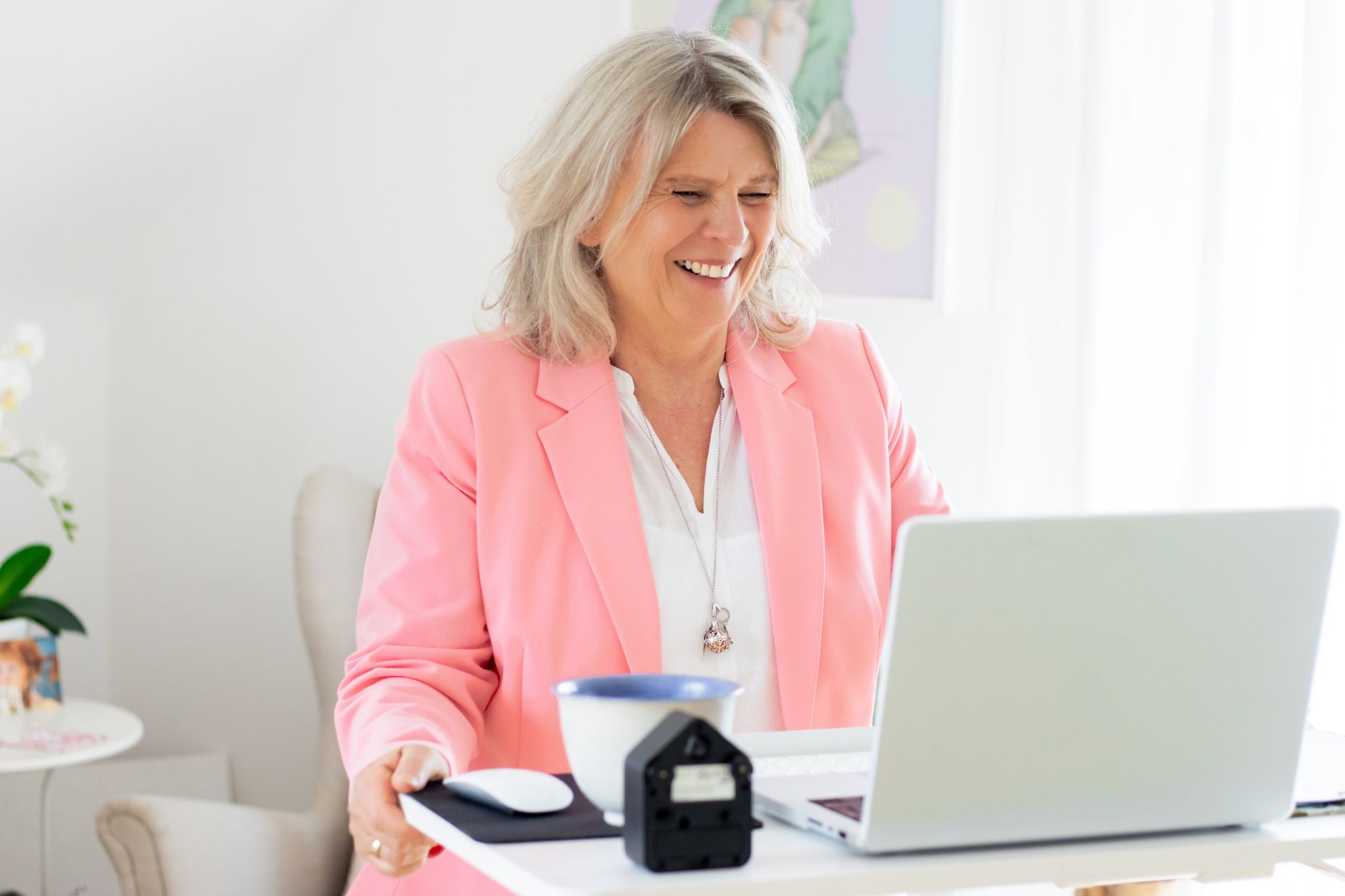 Daniela Brandl steht an einem Hochschreibtisch, vor ihr ein LapTop. Sie lacht in die Kamera.