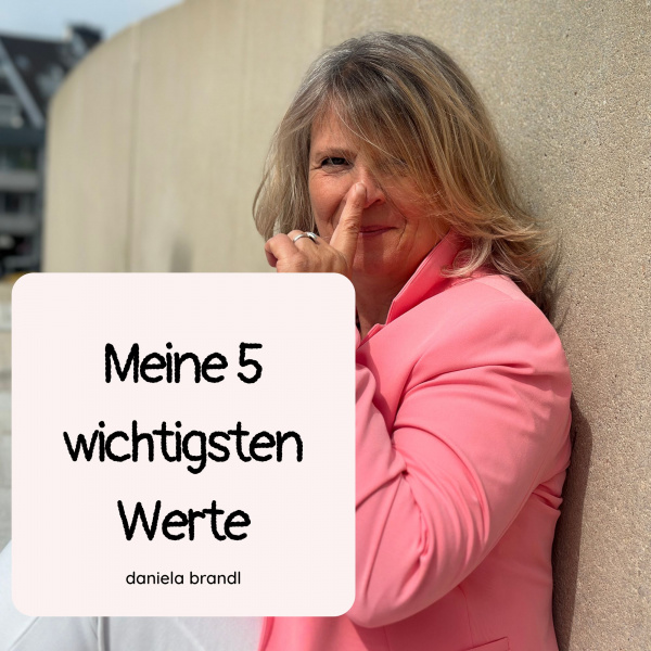 Daniela Brandl sitzt vor einer naturfarbenen Mauer, schaut lächelnd in die Kamera und hält ihren Zeigefinger an ihre Nasenspitze. Auf dem Foto sieht man die Überschrift des Blogartikels: Meine 5 wichtigsten Werte