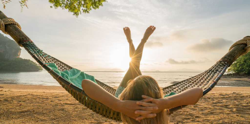 Eine Frau liegt in einer Hängematte mit Blick auf das Meer